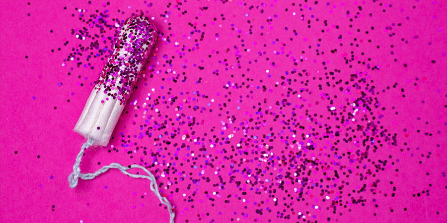 Tampon covered in glitter on a bright hot pink background 